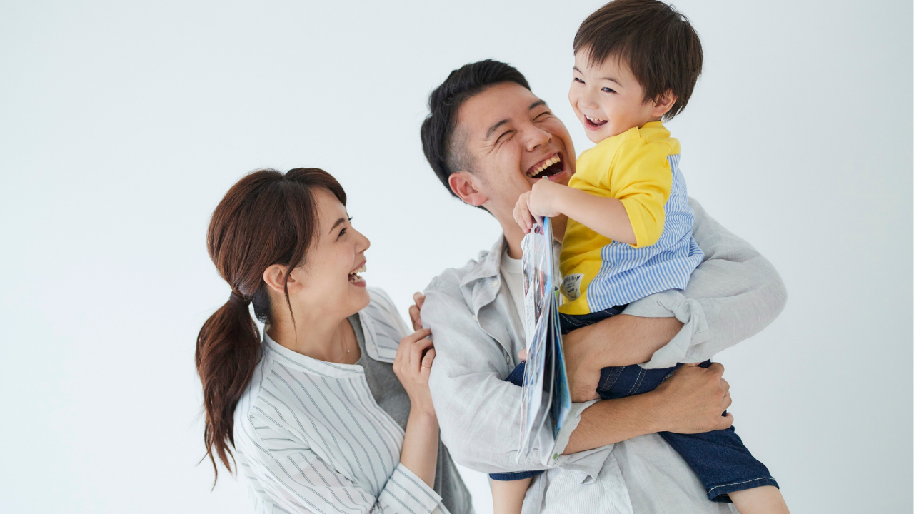 子どもを抱っこして笑う父親と母親　家族で育児を楽しむイメージ