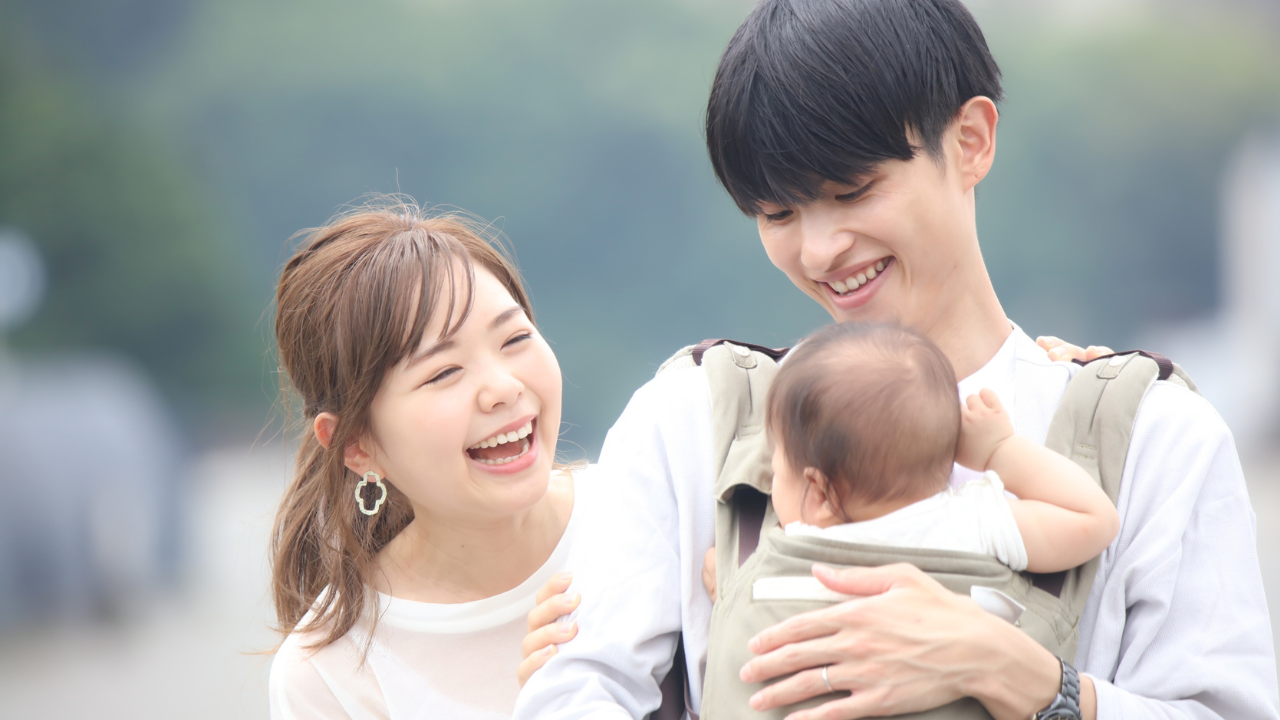 赤ちゃんを抱っこする父親と笑顔の母親　パパの育児参加イメージ